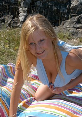 Blonde whore stops on the rocks to suck her huge orange sex toy in the nude