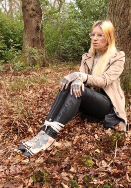 Girl with glasses can't stand up because she is hogtied by the tree