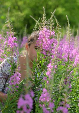 Young babe with a ponytail walks in the field and exposes private parts