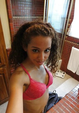 Latina with curly hair is taking sexy selfies while in lingerie