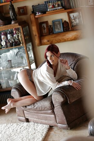 Ravishing redhead seductively walks around living room dressed in lover's jacket