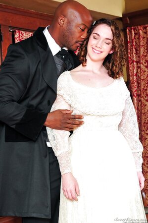 Pale-skinned girl in old-fashioned white dress kisses black man in a suit