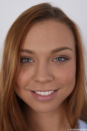 Female with red hair and bright eyes smiles and keenly strips for strangers