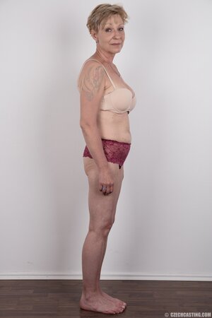 Mature porn model with tattooed shoulder advertises natural twins and slit