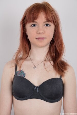 Female with red hair and colored rose tattooed on pale body strips down