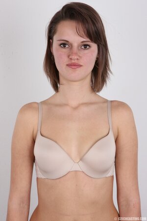 Female smiles so shy but still keeps on stripping naked in photo studio