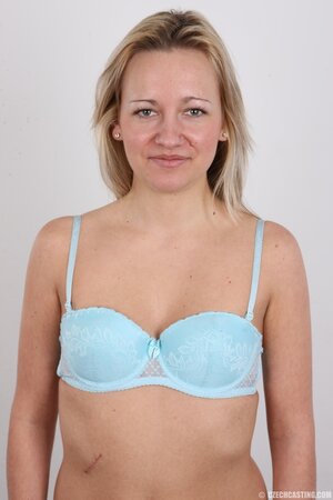 Blonde smiles because of shyness getting clothes off item by item in studio