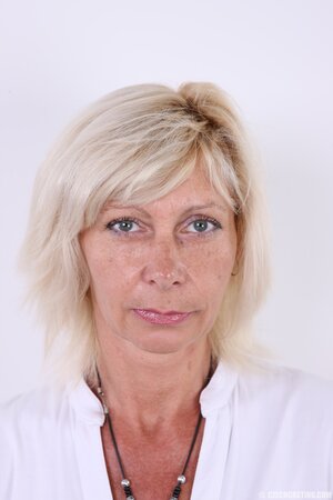 Mature blonde woman gets rid of white dress and lingerie remaining naked