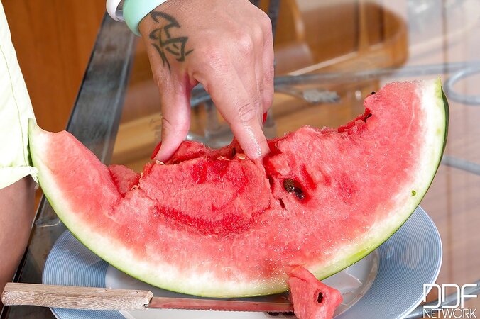 Cute seductress eats watermelon squeezing its juice over hr big naked knockers