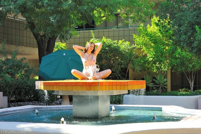 Babe opens naked body to water drops in fountain and stimulates pussy with a comb