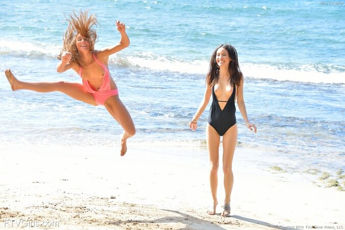 Young women rest together on the ocean shore kissing and unfolding fun parts