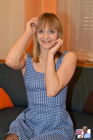 Female in a blue dress never stops smiling while stripping down on camera