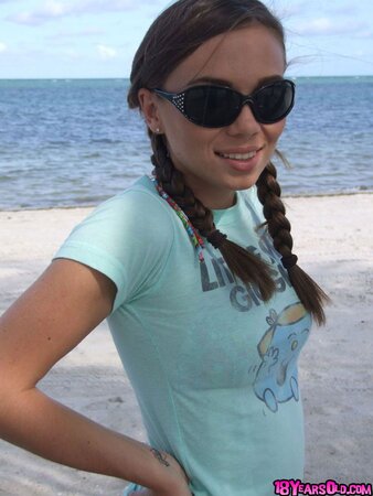 Teen wearing sunglasses comes to the beach where she is going to swim being naked