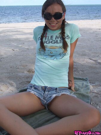 Teen wearing sunglasses comes to the beach where she is going to swim being naked