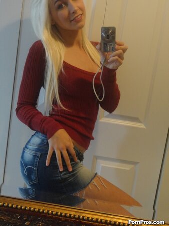 Blonde female with tattooed hands takes boobs to light in front of the mirror