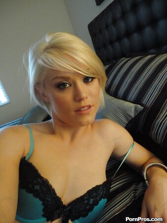 Blonde girl in green lingerie takes nude selfies in front of a big mirror