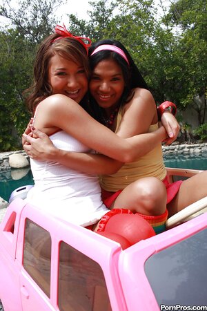 Black girl in pink headband and lesbian friend have fun by Cadillac Escalade toy