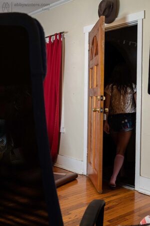 Curvy brunette with messy hair in cute pink socks puts on small shorts
