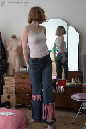 Girl with bangs and hairy pussy puts on clothes in front of the mirror