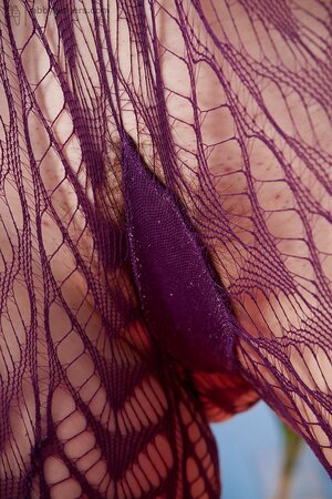 Girl in fishnets pulls them down to brandish her trimmed pussy in the bed