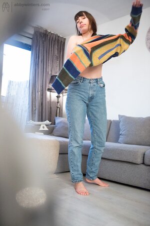 Skinny female pulls on small panties and hides natural boobs with a sweater