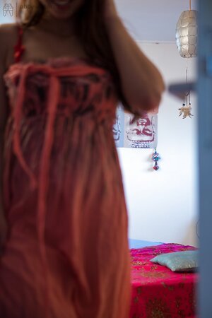 Naked female gets on the bed to put her underwear and long dress on