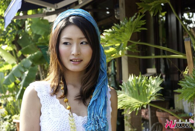 Good-looking Japanese girl in white dress walks into the water being dressed