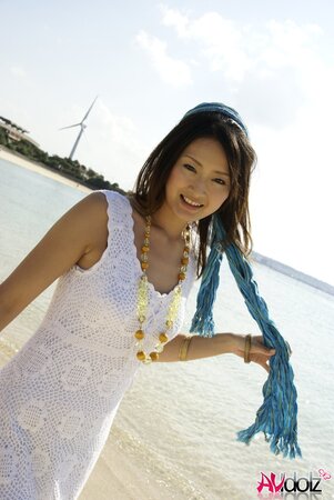 Good-looking Japanese girl in white dress walks into the water being dressed