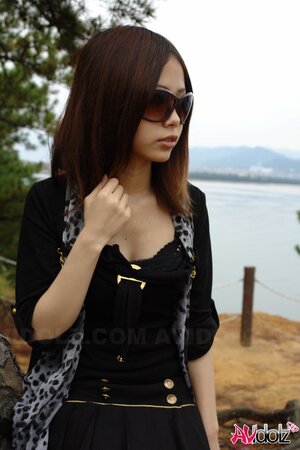 Asian girl with sunglasses on looks so seriously cause she is shy being naked