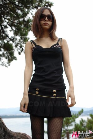 Asian girl with sunglasses on looks so seriously cause she is shy being naked