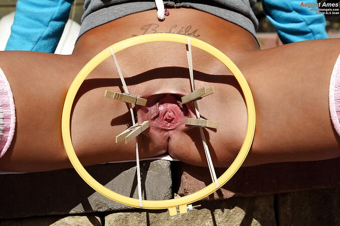 Sporty brunette with natural tits stretches pussy outdoors with a special device