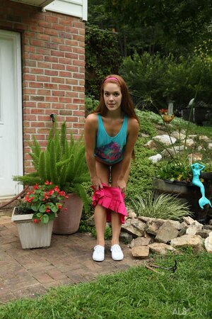 Hungry girl masturbates with a water hose and small rakes in the backyard