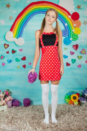 Young woman in a polka-got red dress gets nude in her infantile room