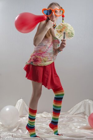 Fancy girl with red balloons and in striped socks bares her small fun parts