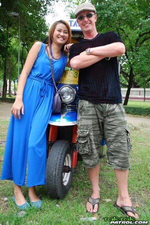 Hot female from Thailand poses in her slinky blue dress by a small taxi