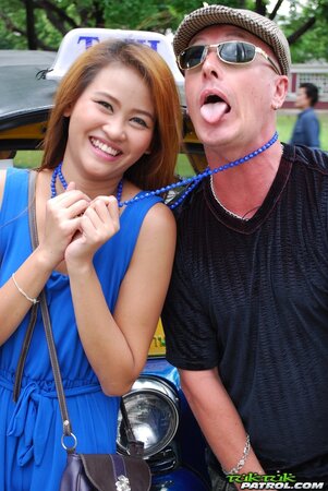 Hot female from Thailand poses in her slinky blue dress by a small taxi