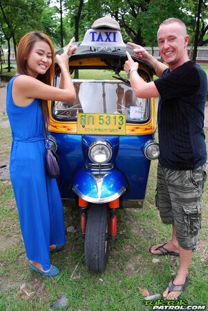 Hot female from Thailand poses in her slinky blue dress by a small taxi