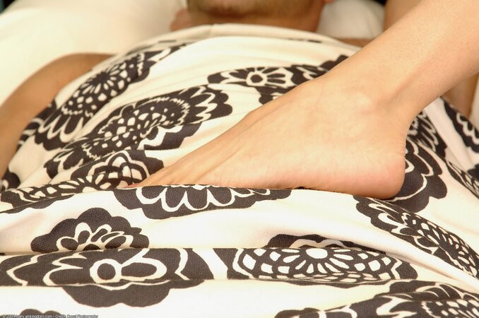 Girl puts her foot on sleeping man waking him up for a morning footjob