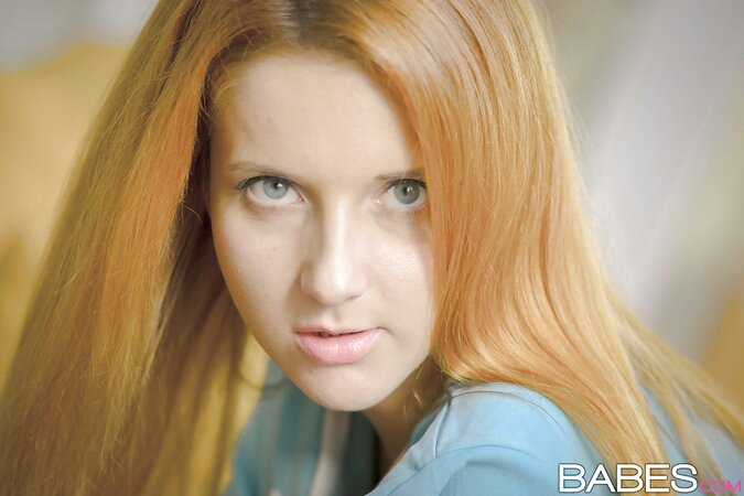 Girl with fire-red hair looks directly into the camera and exposes her slit