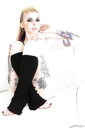Female covered with tattoos puts black leg warmers on to underscore her sexuality