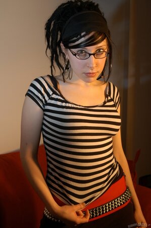 Babe with glasses and pierced nose playfully removes her clothes airing small tits