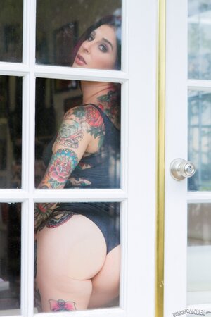 Porn queen strips in front of the glass door and continues posing on the sofa