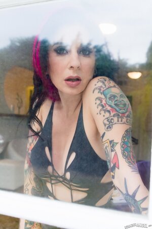 Porn queen strips in front of the glass door and continues posing on the sofa