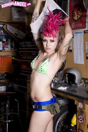Alt girl with bizarre pink hairstyle is possessor of tattoos and pierced nipples