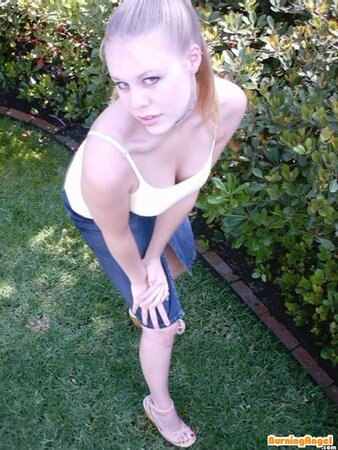 Sexy babe with a ponytail strips down and masturbates her shaved pussy in nature