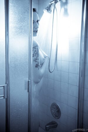 Female with a tattooed body takes a shower and brandishes her private zones