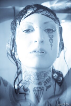 Female with a tattooed body takes a shower and brandishes her private zones