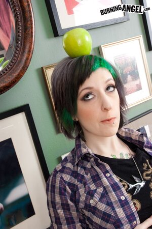 Tattooed coed with green locks eats an apple and fingers vagina on the floor