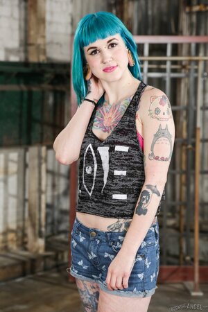 Babe with blue hair in striped stockings has a tattooed body to expose on a bench