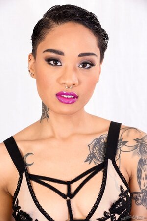 Tattooed oriental love with purple lipstick looks into the camera and gets naked